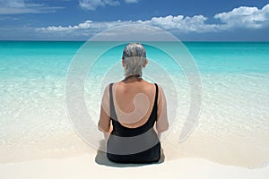 Senior looks out on ocean from serene beach in the Caribbean