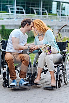 Senior loving couple sitting in the wheelchairs outdoors