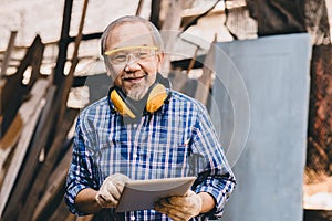 Senior male Asian worker builder happy smile with safety equipment work in wood construction site