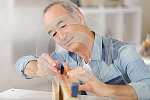 senior male carpenter using level on wood board