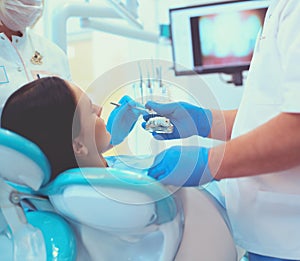 Senior male dentist in dental office talking with female patient and preparing for treatment