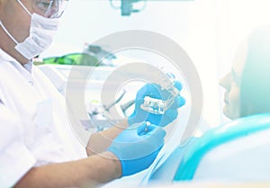 Senior male dentist in dental office talking with female patient and preparing for treatment