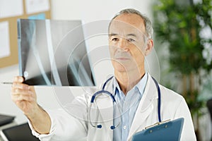 senior male doctor holding x-ray image