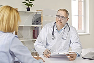 Senior male doctor is listening to his female patient during medical consultation