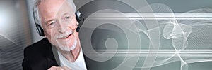 Senior male helpline operator in headset; panoramic banner