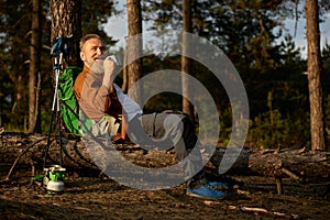 Senior male hiker taking coffee break during active walk adventure outdoors