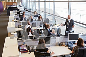 Senior male manager addressing workers in open plan office