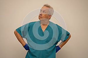 Senior male nurse with hands on hips glancing upward away from camera