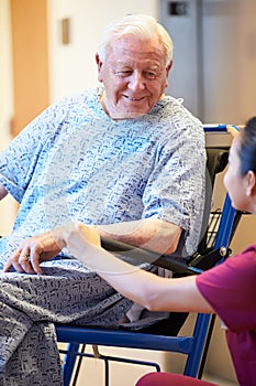 Senior Male Patient Being Pushed In Wheelchair By Nurse