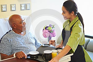 Senior Male Patient Being Served Meal In Hospital Bed