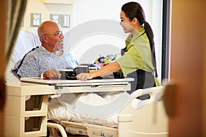 Senior Male Patient Being Served Meal In Hospital Bed