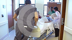 Senior Male Patient Being Wheeled Along Hospital Corridor