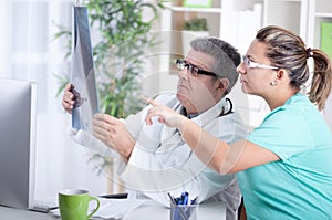 Senior male radiologist and female patient looking at x-ray