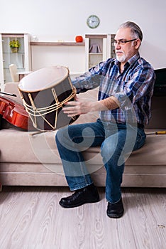 Senior male repairman repairing musical instruments at home