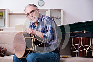 Senior male repairman repairing musical instruments at home