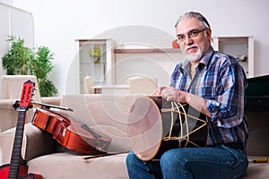 Senior male repairman repairing musical instruments at home