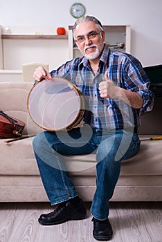 Senior male repairman repairing musical instruments at home