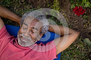 Senior male resting with closed eyes on exercise mat