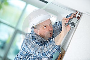 Senior male technician installing camera on wall