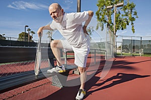 Senior male tennis player with back pain on court