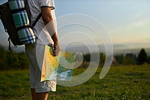 Senior male traveler holding touristic map, while backpacking in mountains.