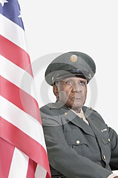 Senior male US military officer with American flag against gray background