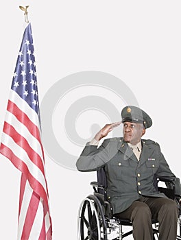 Senior male US military officer saluting American flag over gray background