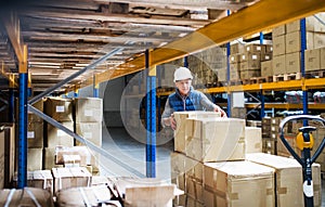 Senior male warehouse worker unloading boxes from a pallet truck.