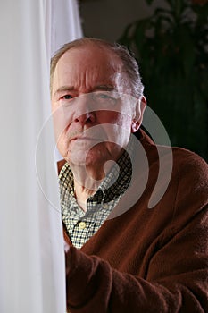 Senior male by window with serious expression