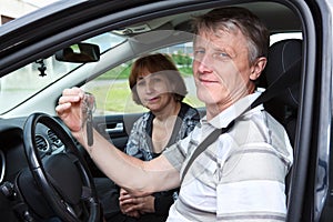 Senior male and woman sitting in car and smiling