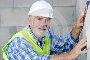 senior male worker measuring wall