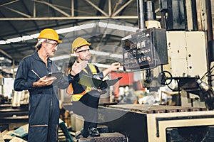 senior male worker training new young engineer employee working in heavy industry metal factory