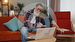 Senior man accounting payments calculating monthly expenses bank bills, analysing paperwork at home