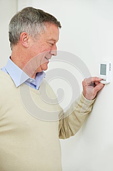 Senior Man Adjusting Central Heating Thermostat