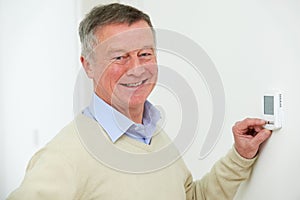 Senior Man Adjusting Central Heating Thermostat