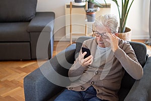 Senior man adjusting glasses while reading sms