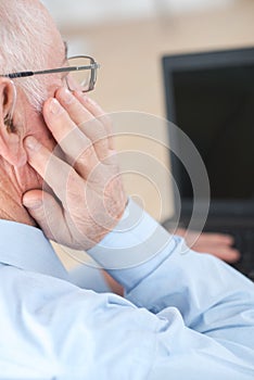 Senior man adjusting hearing aid