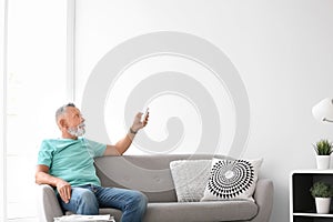 Senior man with air conditioner remote contro photo