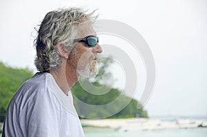 Senior man alone feeling emotional & thoughtful looking at ocean