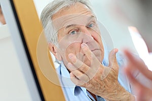 Senior man applying anti-aging lotion for skin