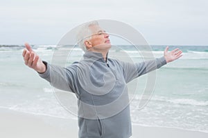 Senior man with arms outstretched at beach