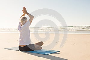 Senior man with arms raised meditating at beach