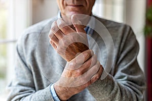 Senior man with arthritis rubbing hands photo