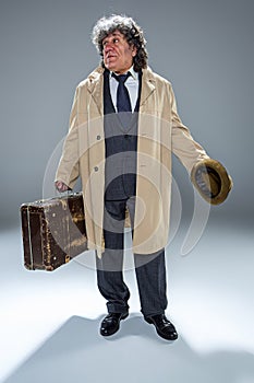 The senior man as detective or boss of mafia on gray studio background