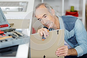 Senior man assembling fitted kitchen