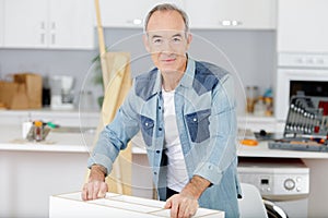 senior man assembling flat pack furniture