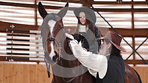 Senior man assisting granddaughter horseback riding in ranch