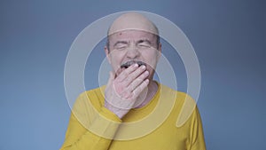 Senior man being bored yawning tired covering mouth with hand