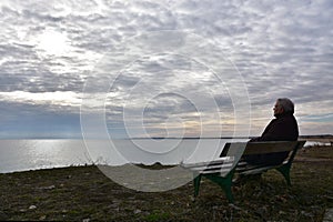 Senior man on a bench watching winter seascape