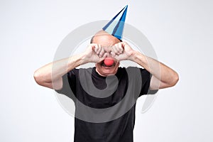 Senior man in birthday cap crying and wiping tears on his party